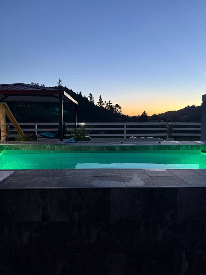 Piscina de Campo Bello iluminada al atardecer entre las montañas de Orocovis