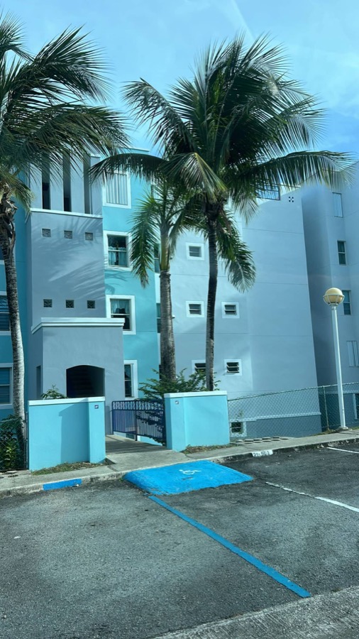 Edificio turquesa de Costa Bella entre palmeras en Ceiba